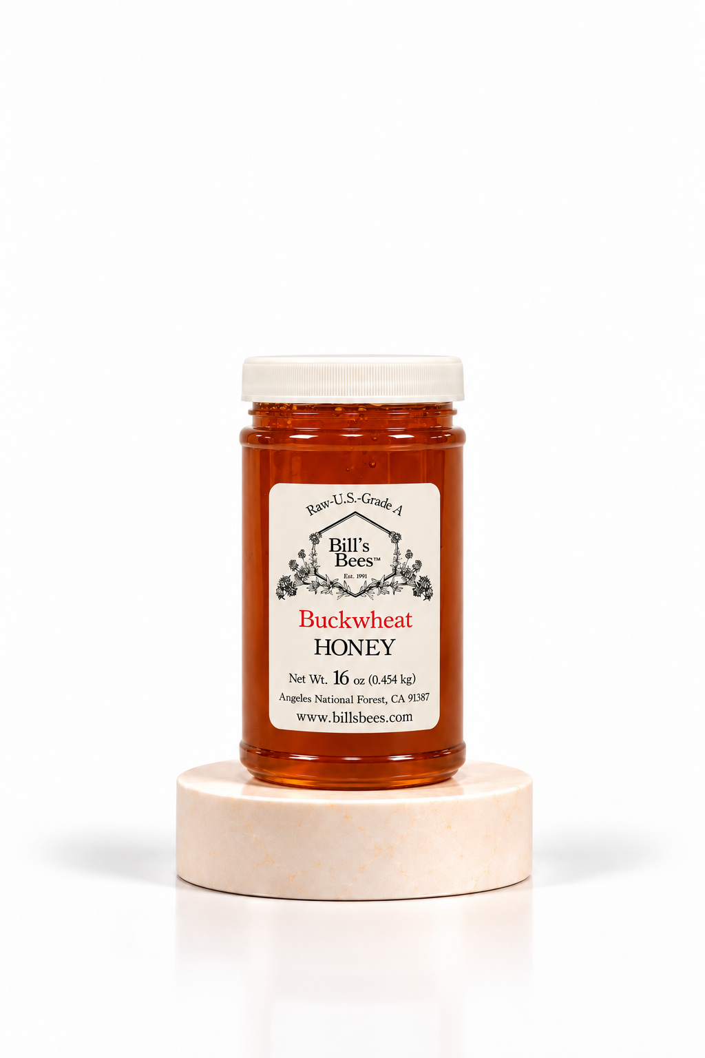 16 oz Bill's Bees Buckwheat Honey jar on a marble pedestal, portrait format