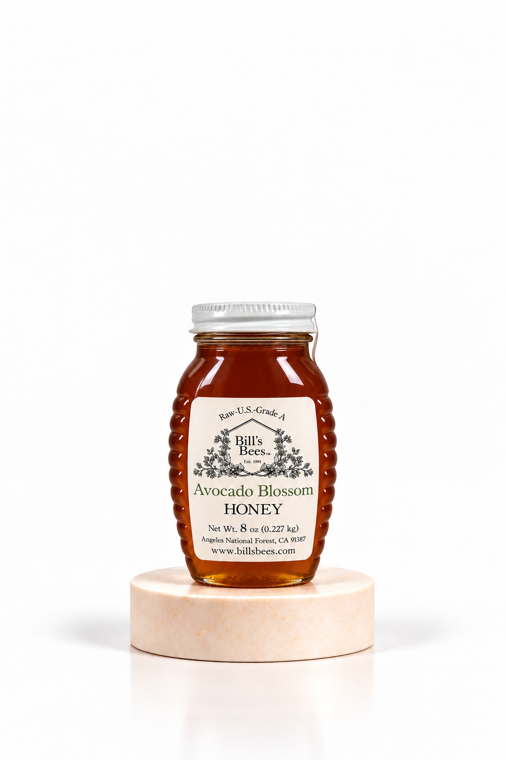 8 oz Bill's Bees Avocado Blossom Honey jar on a marble pedestal, portrait format